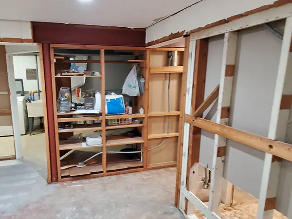 Partially constructed basement with exposed framing and built-in shelving, showing the remodeling process.