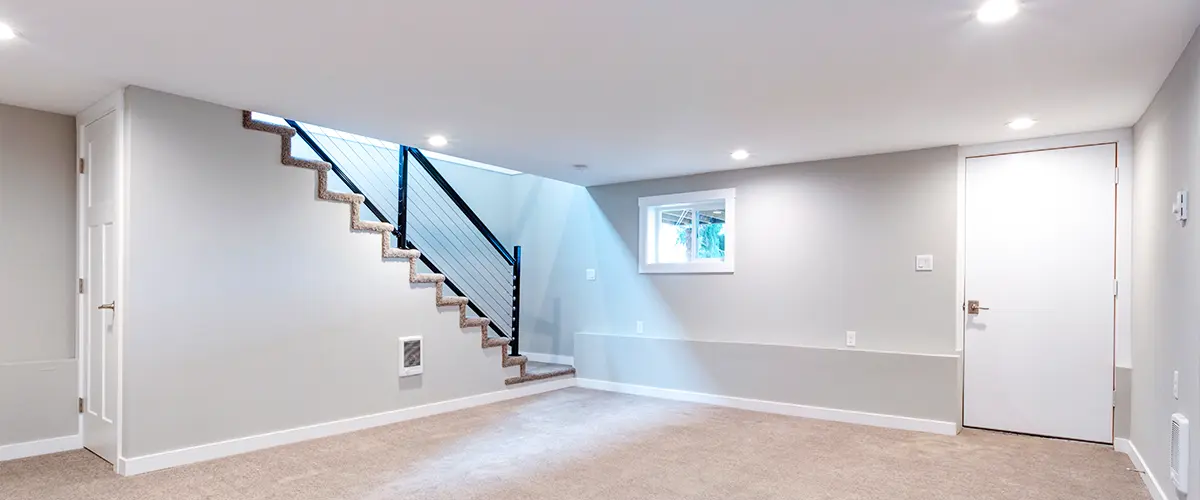 Spacious finished basement with soft carpet, recessed lighting, and a sleek staircase, ideal for home renovations.